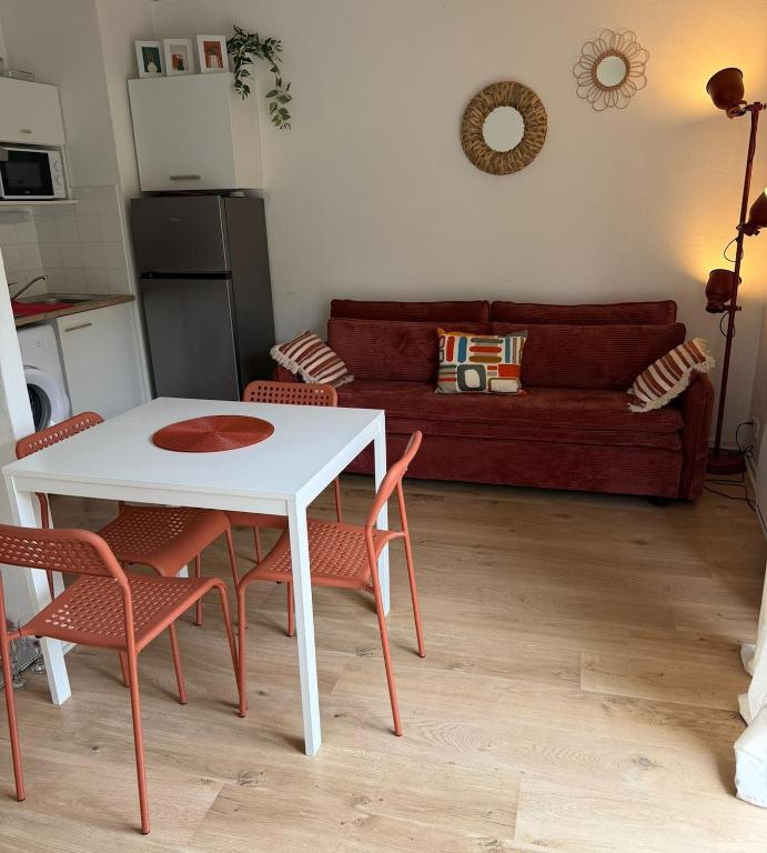 a living room with a table and chairs and a couch at Appartement La Parenthèse Verte - Capvern in Capvern