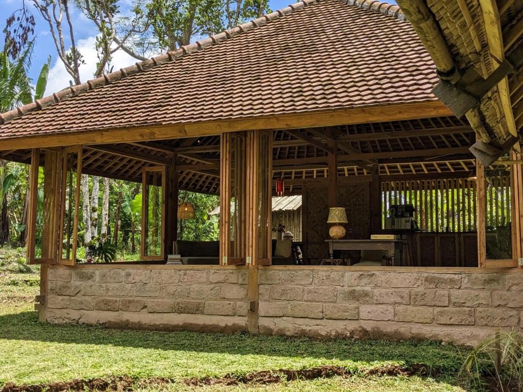 a wooden pavilion with a table in a yard at Cosy Cottage Living Harmoniously in Tabanan