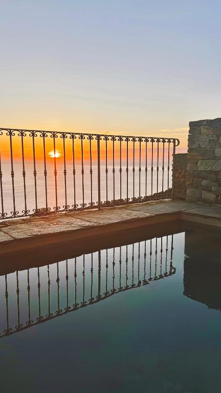 Sonnenuntergang über dem Meer mit einem Zaun und Wasser in der Unterkunft Cap Hélios, vue mer à couper le souffle à Centuri in Morsiglia