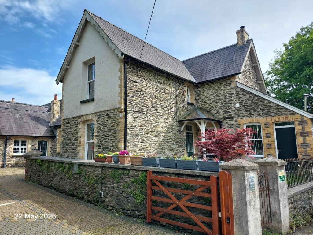 an old stone house with a wooden gate at Old School B & B in Llandysul