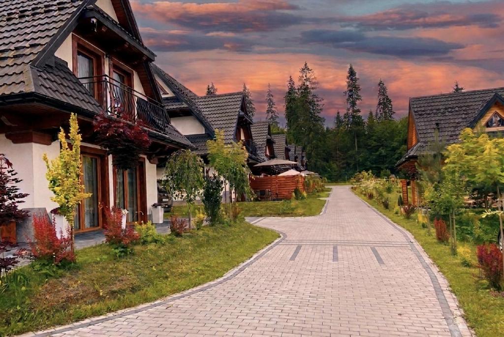 a cobblestone road in a village with houses at Domki Pod Lasem Podhale in Zakopane