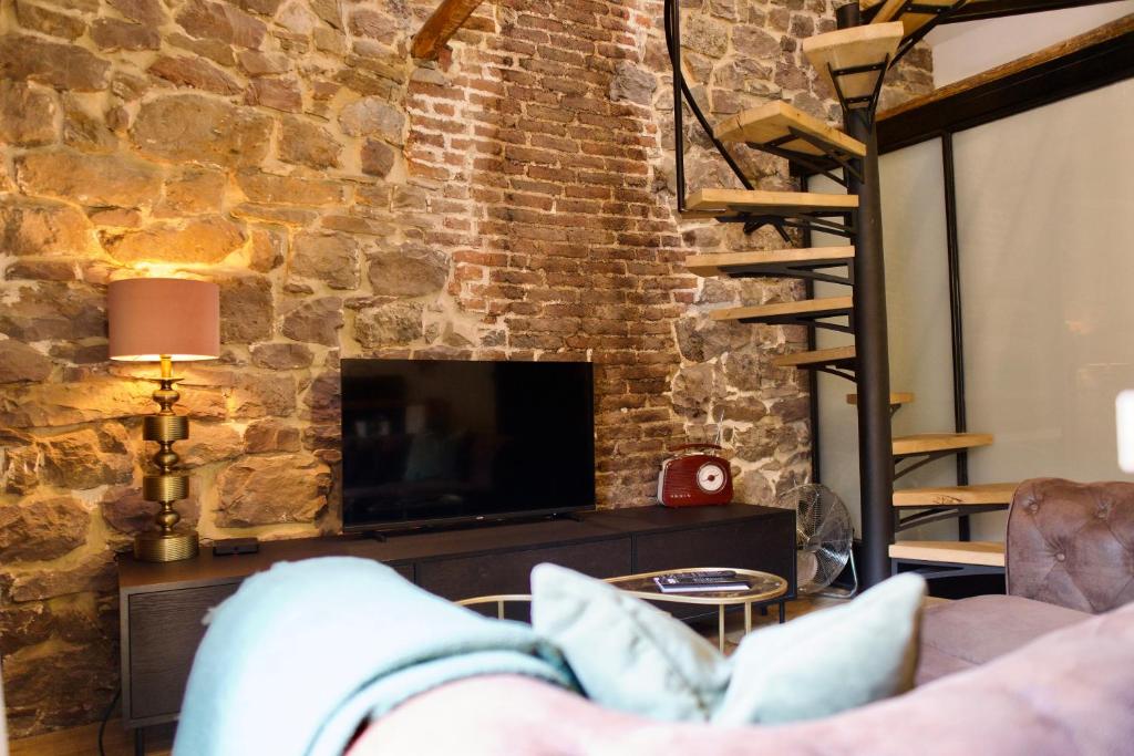 a living room with a brick wall and a tv at Loft urbain style Brooklyn in Profondeville