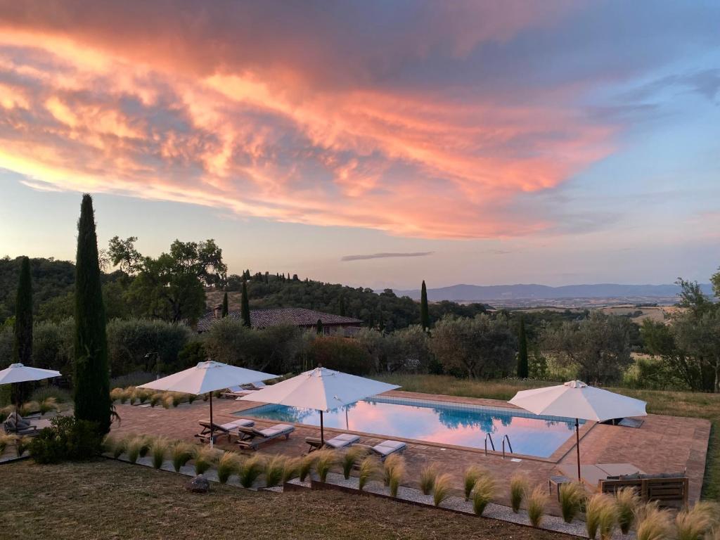 a villa with a swimming pool and umbrellas at Abbadia Wine Relais in Montefollonico