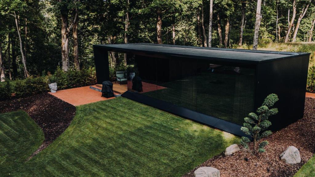 a black house in a garden with a lawn at Stars Resort Sigulda in Sigulda