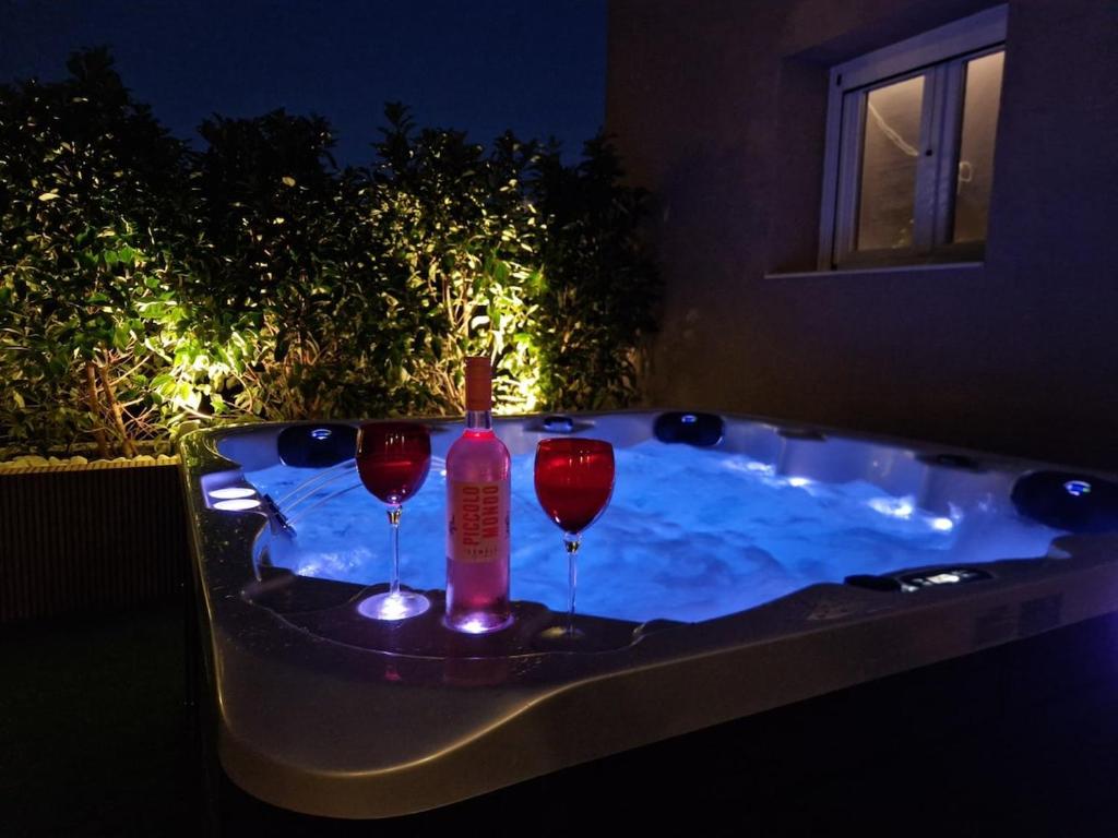 a hot tub with two wine glasses and a bottle at Alykes Maisonette Prv Jacuzzi in Kontokali