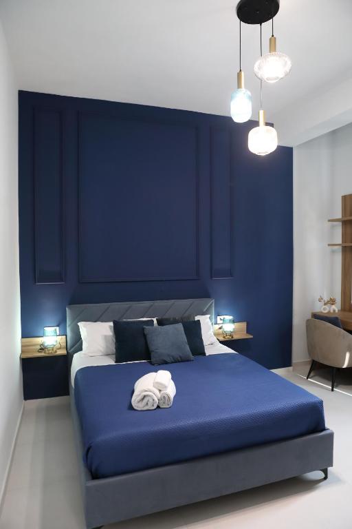 a blue bedroom with a bed with towels on it at Alcenide Aparthotel in Villa San Giovanni