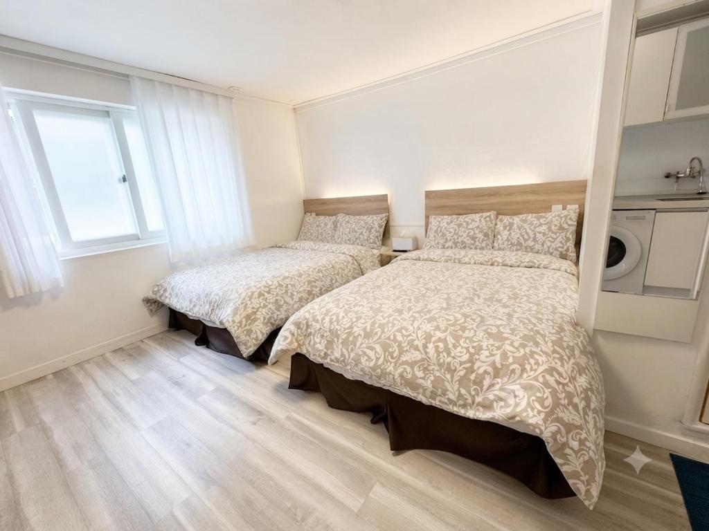 a white bedroom with two beds and a window at Seoul Mansion Guesthouse in Seoul