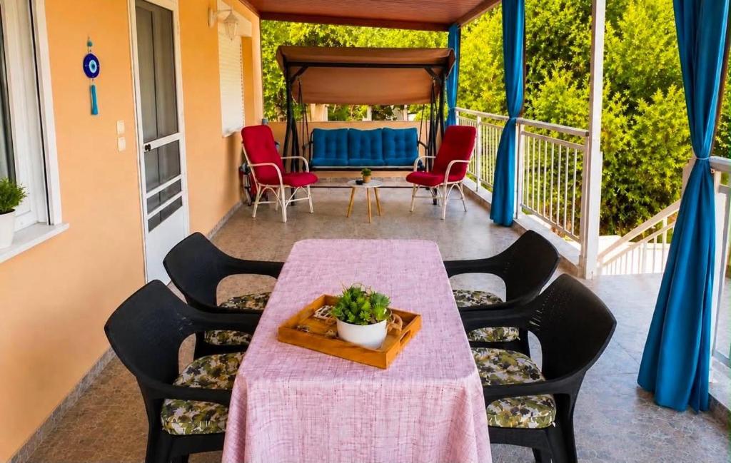 a table and chairs on a porch with a pink tablecloth at Joan's House in Nea Potidaea