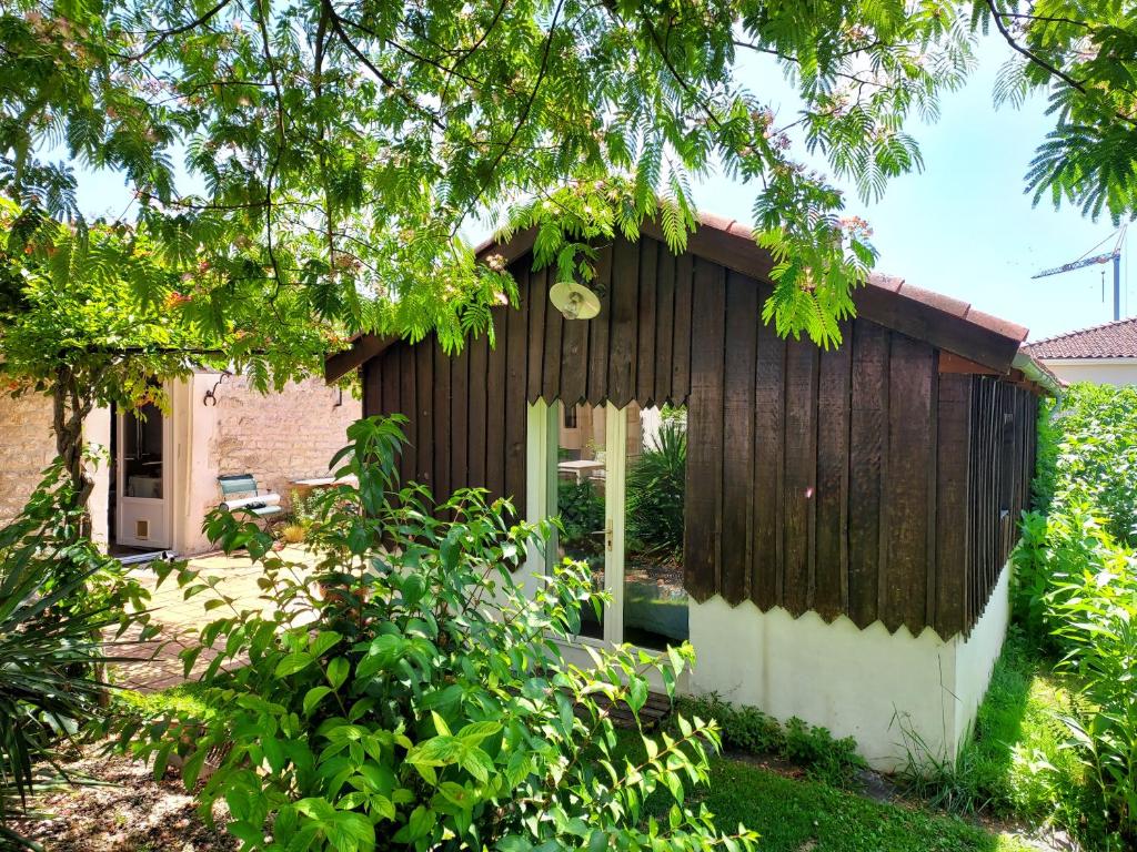 a small house with wooden siding in a garden at Cabane & Jardin in La Tremblade