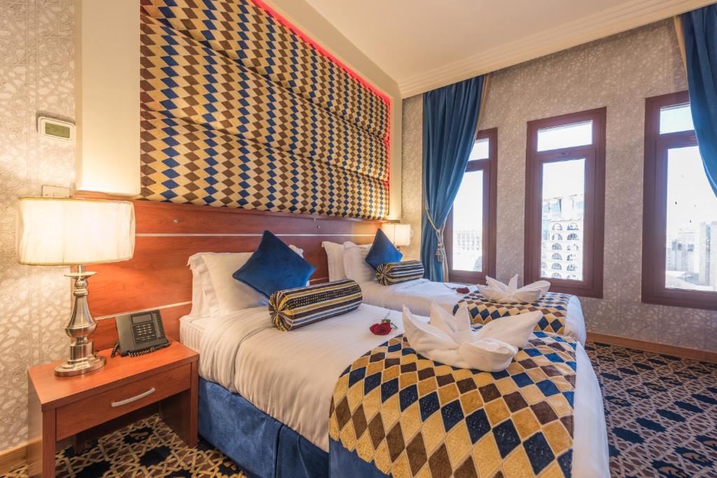 a hotel room with two beds with blue curtains at Nusk Al Madinah in Medina