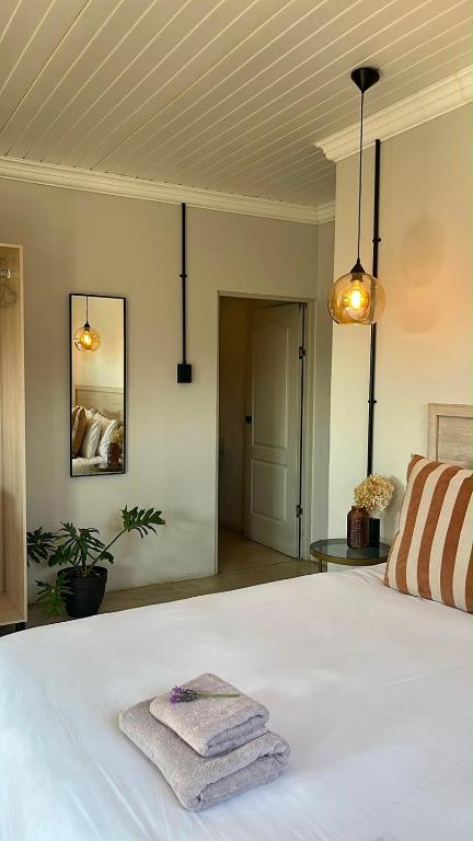 a bedroom with a white bed with two towels on it at Lighthouse Guesthouse & Cafe in Groblersdal