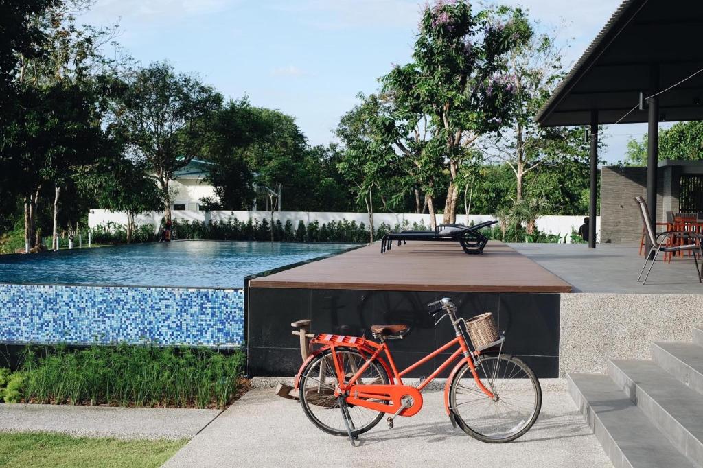 a red bike is parked next to a pool at Riverawan Hotel in Chanthaburi