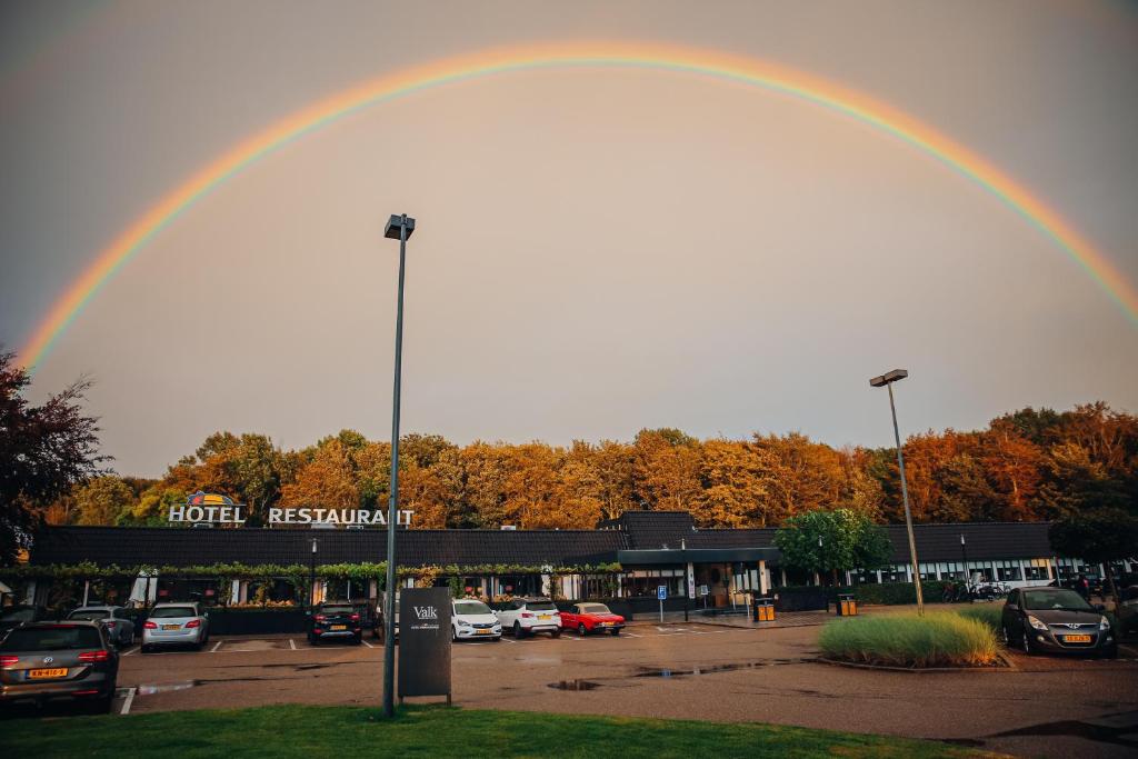 a rainbow over a parking lot with cars parked at Van der Valk Hotel Hollands Kroon in Wieringerwerf