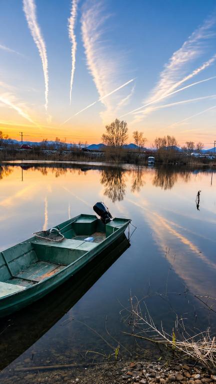 a boat sitting on the water at sunset at Apartments Skadar Lake in Vranjina