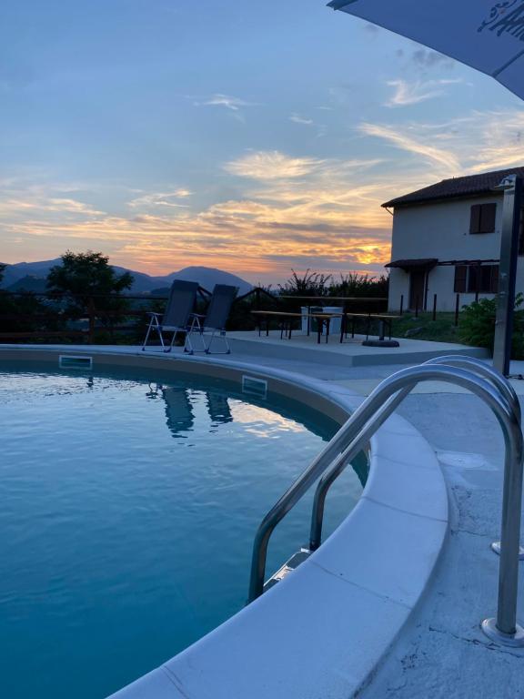 a swimming pool with two chairs and a sunset at Alta Quiete in Frontone