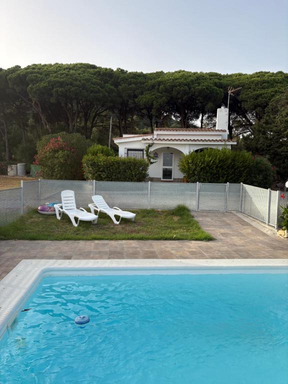 a swimming pool with two chairs and a house at Finca Dos Vientos Tarifa in Tarifa