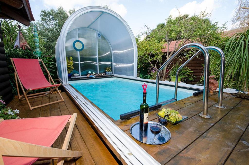 a swimming pool with a bottle of wine and a wine glass at Lodge On The Sea in Shave Ẕiyyon