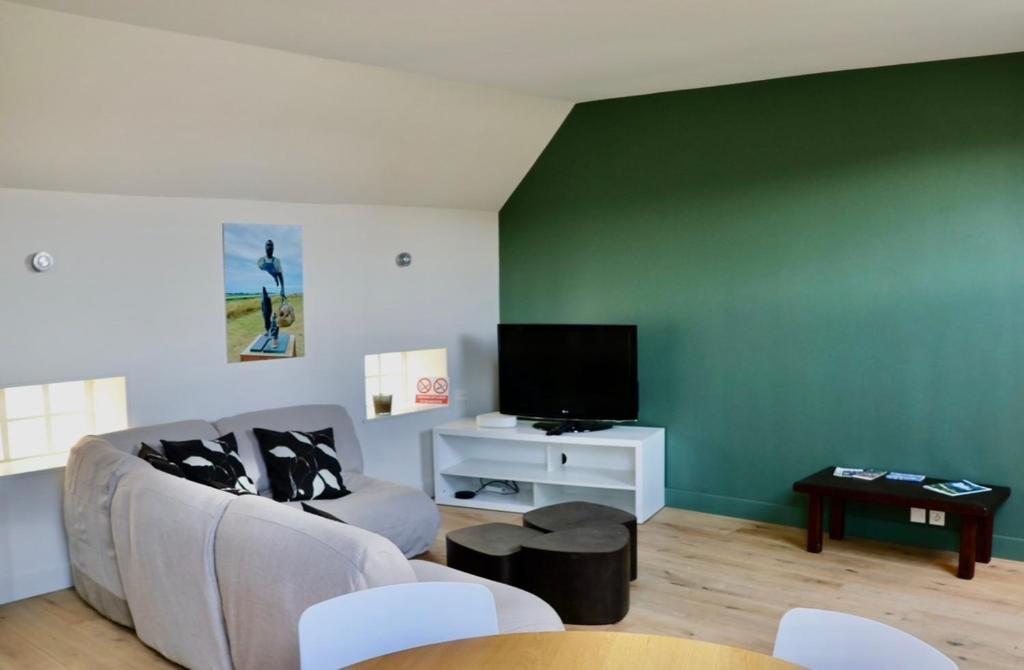 a living room with a couch and a flat screen tv at La Marée Grand appartement à 5 min du Touquet in Étaples