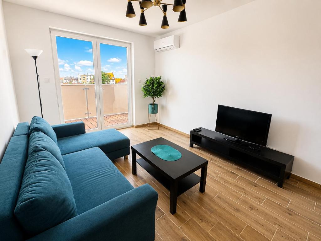 a living room with a blue couch and a tv at Apartament Dolina Baryczy in Żmigród