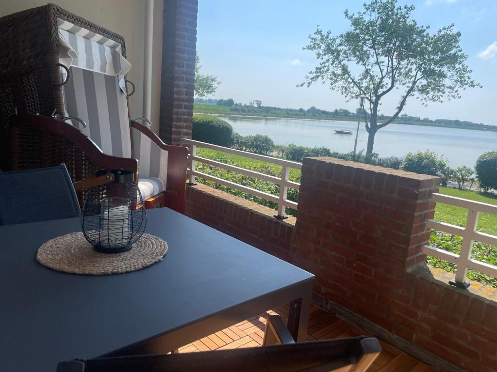 a table and chairs on a balcony with a view of a river at Ferienwohnung Sundkieker Fehmarn in Fehmarn