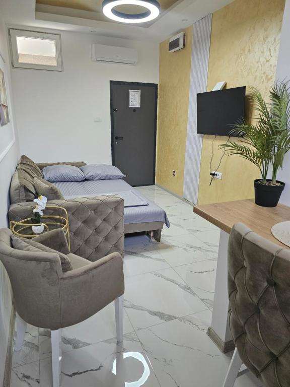 ein Wohnzimmer mit Sofa, Tisch und Stühlen in der Unterkunft Studio centar Lazic 2 in Šid