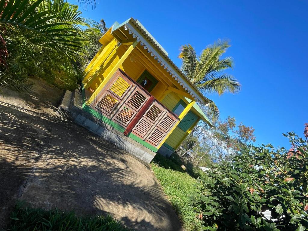 a yellow and green house with a palm tree at Les Chalets de COCO in Saint-Leu