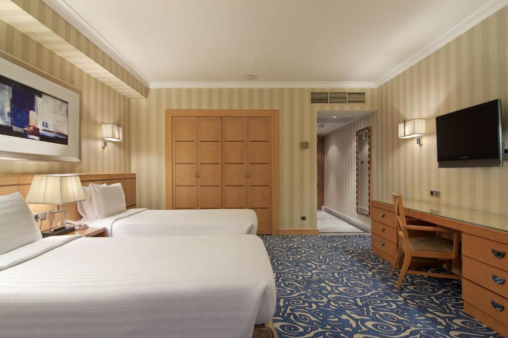 a hotel room with two beds and a flat screen tv at Makkah Towers in Mecca