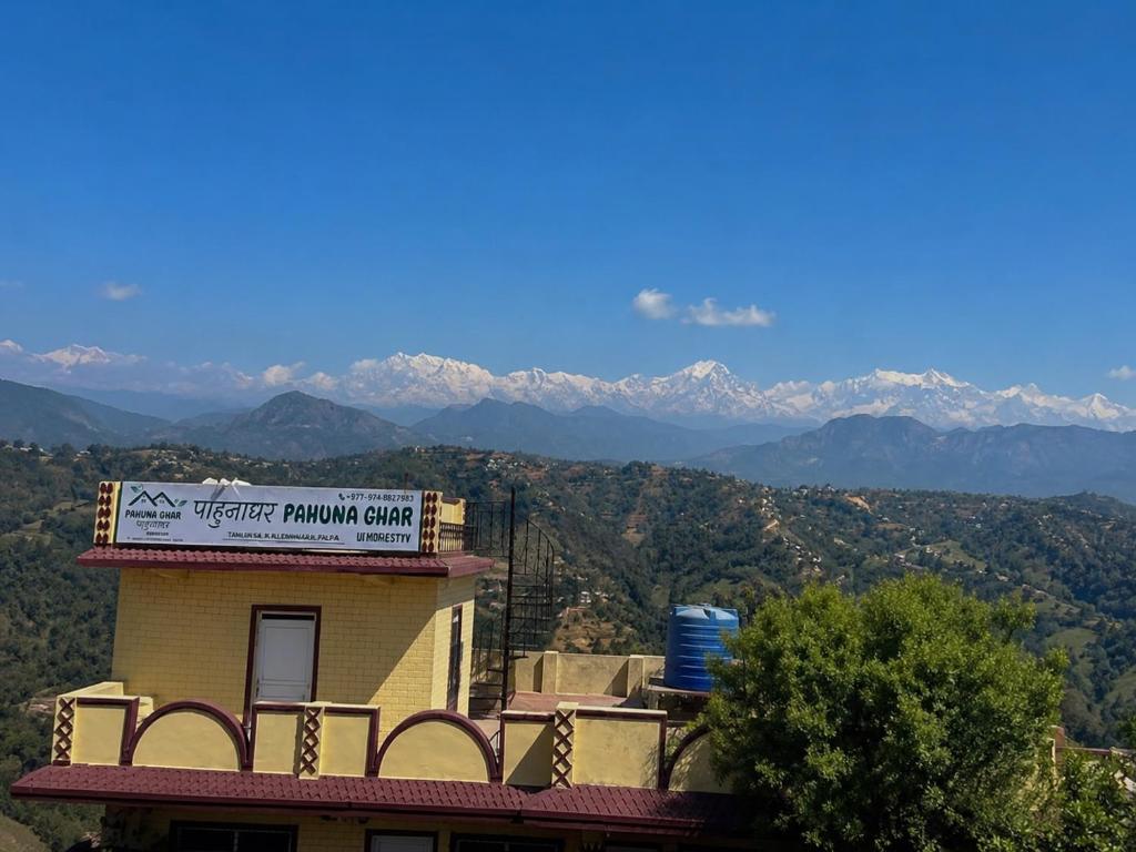 a building with a sign on it with mountains in the background at Pahuna Ghar Homestay in Tānsen