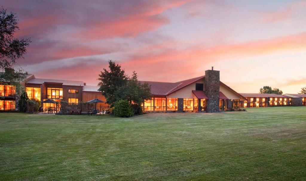 a large building on a field with a sunset at Distinction Mackenzie Country Hotel in Twizel