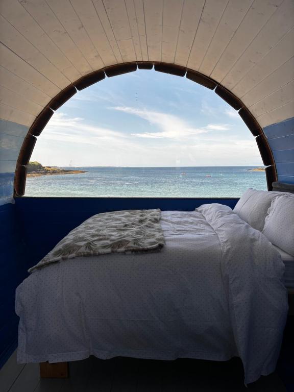 a bedroom with an ocean view from a window at Glamping Pod in Milltown Malbay