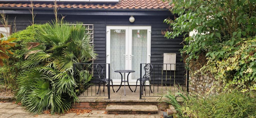 a black house with a table and chairs on a porch at Blackberry Cottage, Wood Farm in Shipdham
