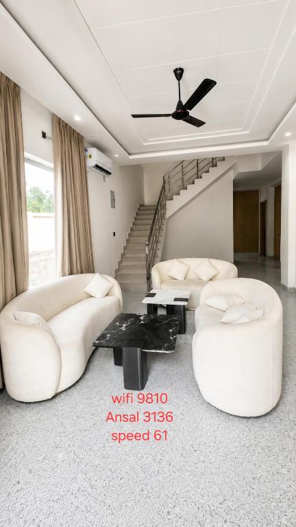 a living room with white furniture and a staircase at Mountain top farmhouse in Gurgaon