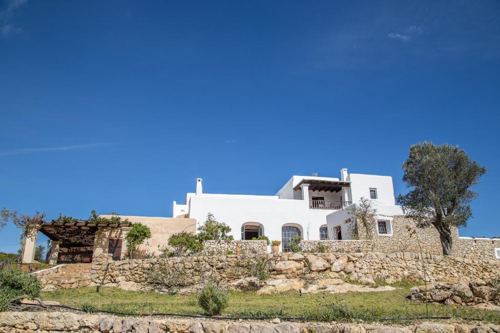 una casa blanca en la parte superior de una pared de piedra en Hotel Rural Can Pujolet en Santa Inés