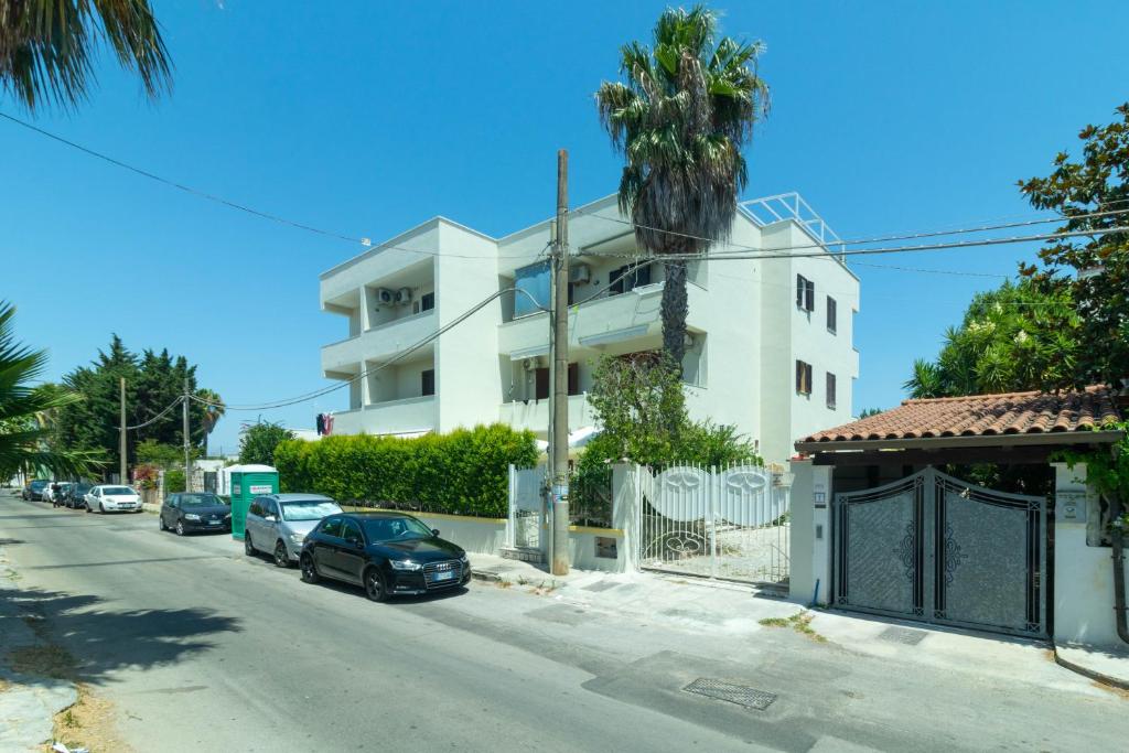 a white building with cars parked on the side of a street at Casa vacanza Appartamento Samari Three in Baia Verde
