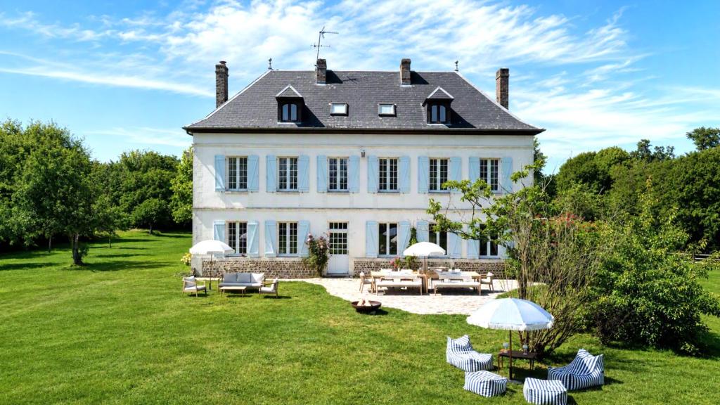 a large white house with chairs and tables in the yard at Clos de Gauville in Brétigny