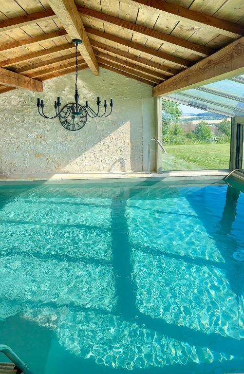 a swimming pool with blue water and a wooden ceiling at Domaine Léa Chanflaur - Spa - La maison du bonheur in Terraube