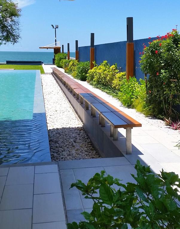 a bench next to a pool with the ocean in the background at Baan Thew Talay Blue Sapphire in Cha Am
