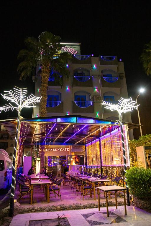 a hotel with tables and lights in front of a building at Golden Sun Hotel - Hurghada in Hurghada
