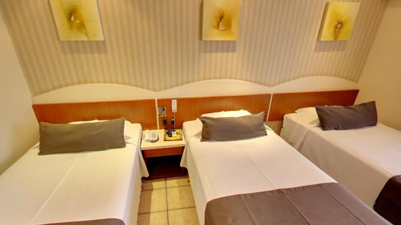 a hotel room with two beds and a desk at Pousada dos Girassóis in Palmas
