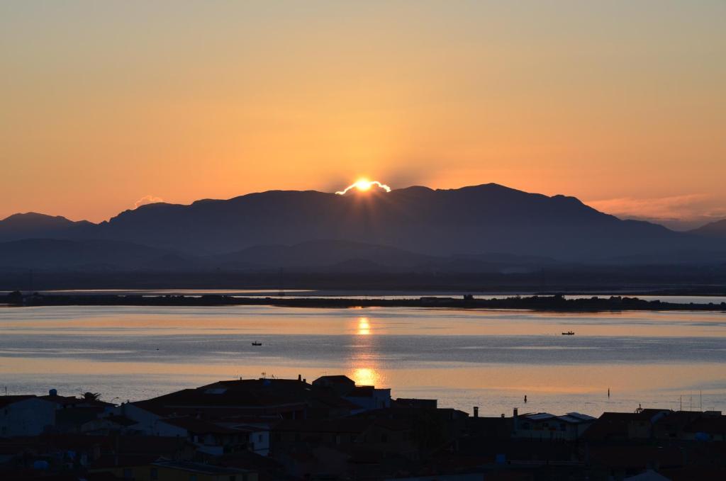 una puesta de sol sobre el agua con una montaña en el fondo en B&B Belvedere, en SantʼAntìoco