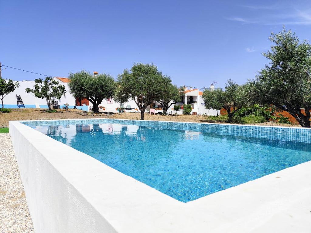 a swimming pool with blue water in front of a house at Refúgio do Artur - Casa no Campo in São Marcos do Campo