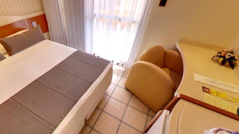 a bedroom with a bed and a chair and a window at Pousada dos Girassóis in Palmas