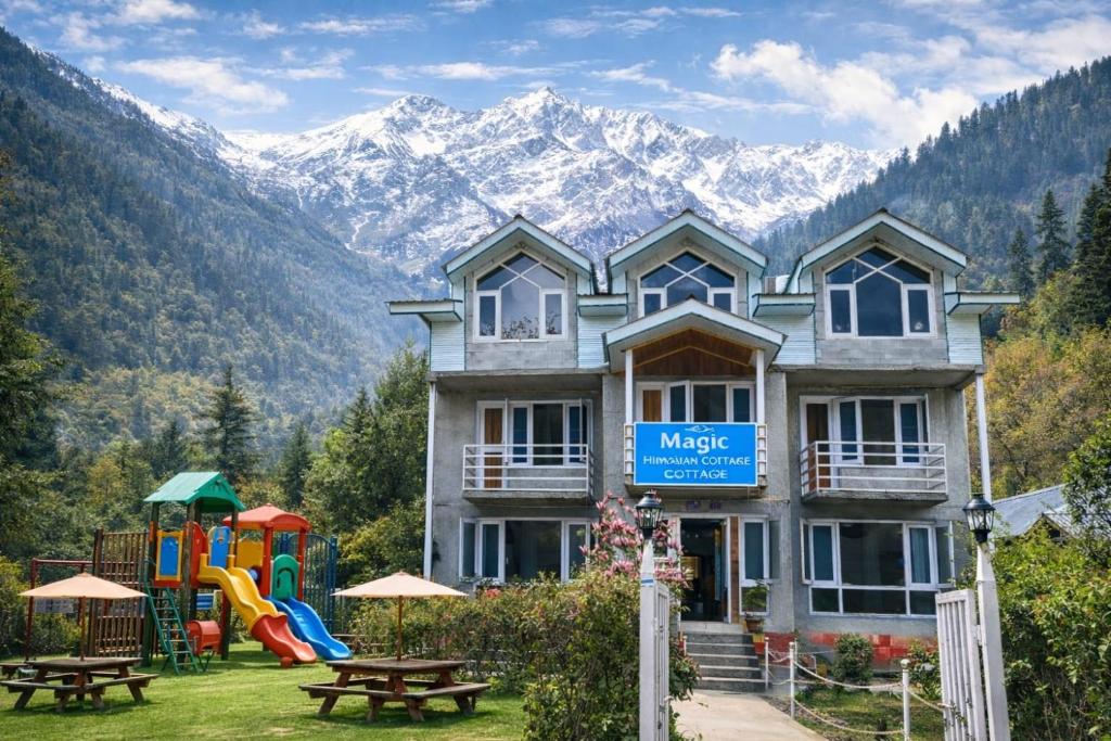 a building with a playground in front of a mountain at Himalayan Cottages Pahalgam in Pahalgām