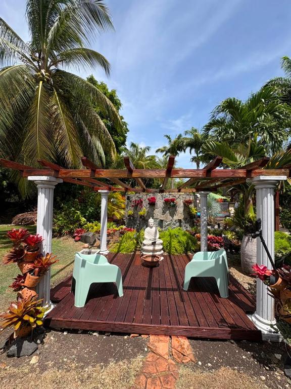a wooden deck with benches and a palm tree at Gite d'Arles Bungalow "Orchidée" in Le Moule