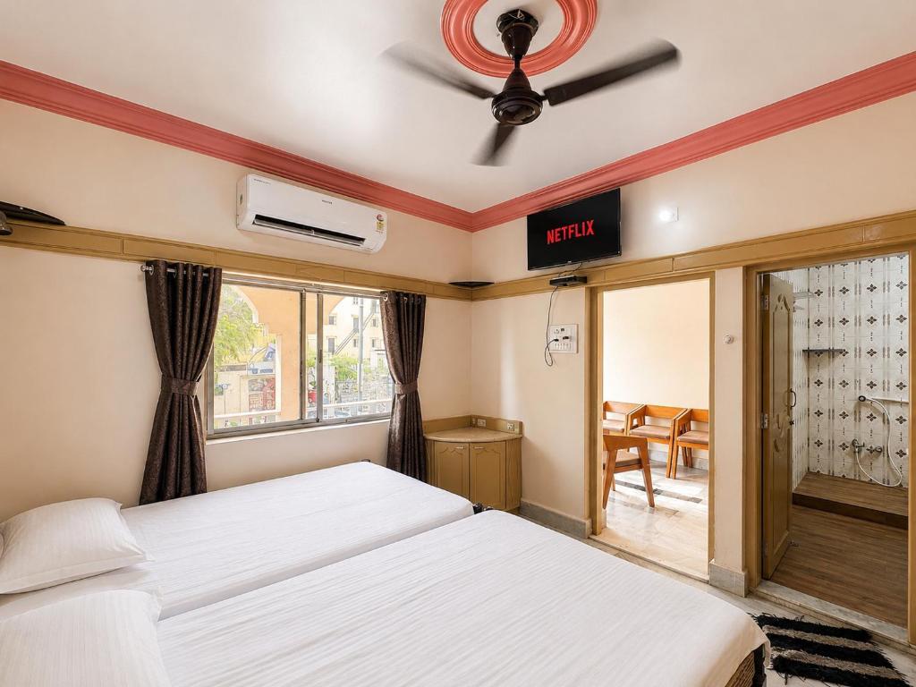 a bedroom with two beds and a ceiling fan at Evergreen Bungalows in Dwarka
