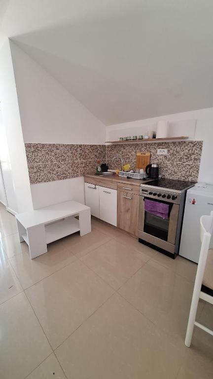 a white kitchen with a stove and a white bench at Coco free parking in Pržno