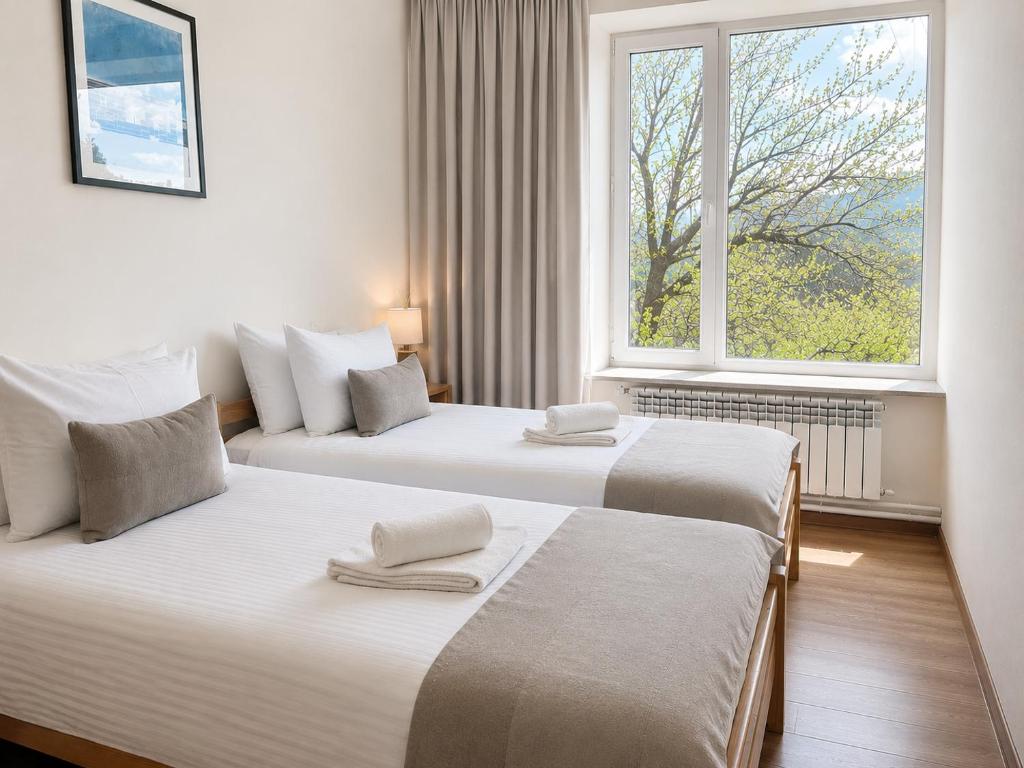 two beds in a room with a window at Hotel Basen in Sisian