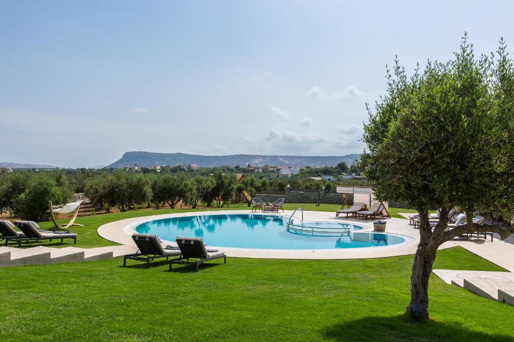 a swimming pool in a yard with chairs and a tree at Aelia Residence, Wellness & Leisure with Heated Pool, By ThinkVilla in Skaleta