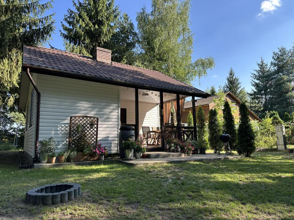 a small white house with a porch at Domek Pod Świerkami in Wólka
