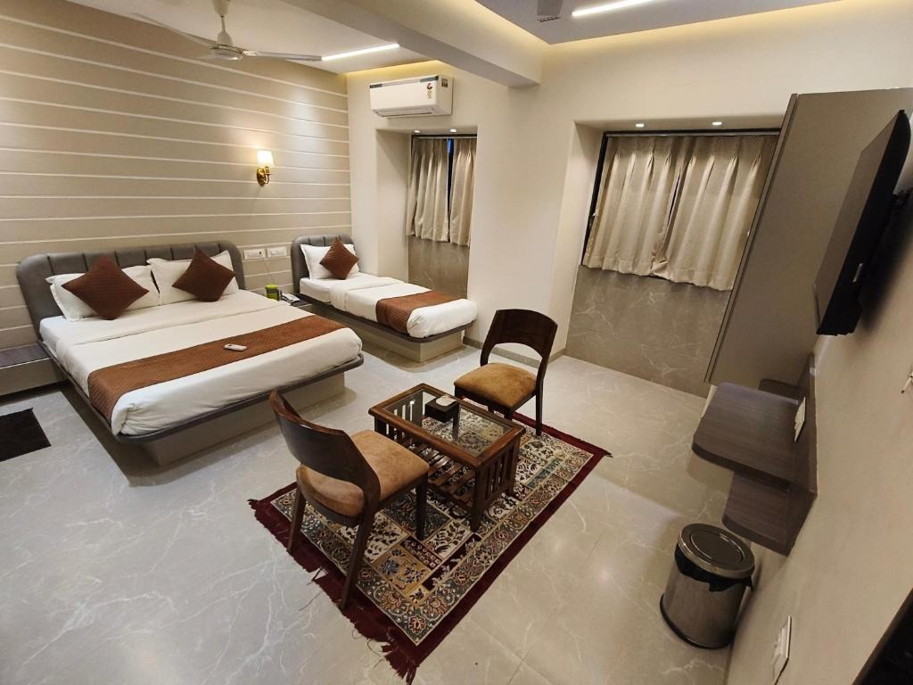 a bedroom with a bed and a couch and a table at Hotel Le Glance Rooms & Dormitory in Mumbai